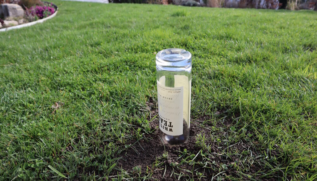 Das Foto zeigt eine leere Schnapsflasche, die in einem Maulwurfgang steckt