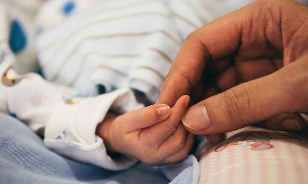 Das Foto zeigt eine Erwachsenenhand die eine Kinderhand hält