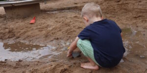 Das Foto zeigt einen Jungen, der im Sand spielt