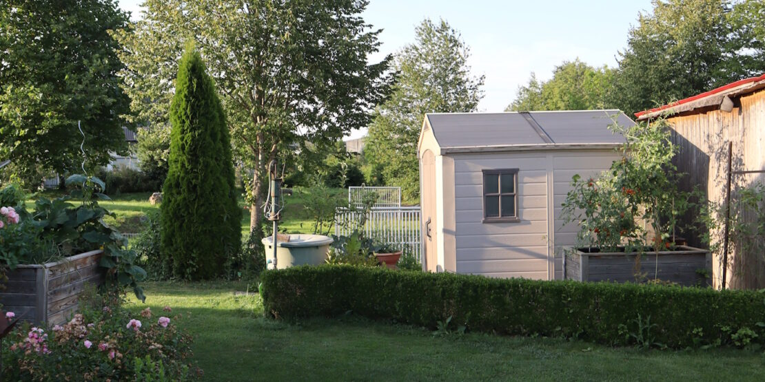 Das Foto zeigt einen Gartenabschnitt mit Häuschen und Wasserpumpe