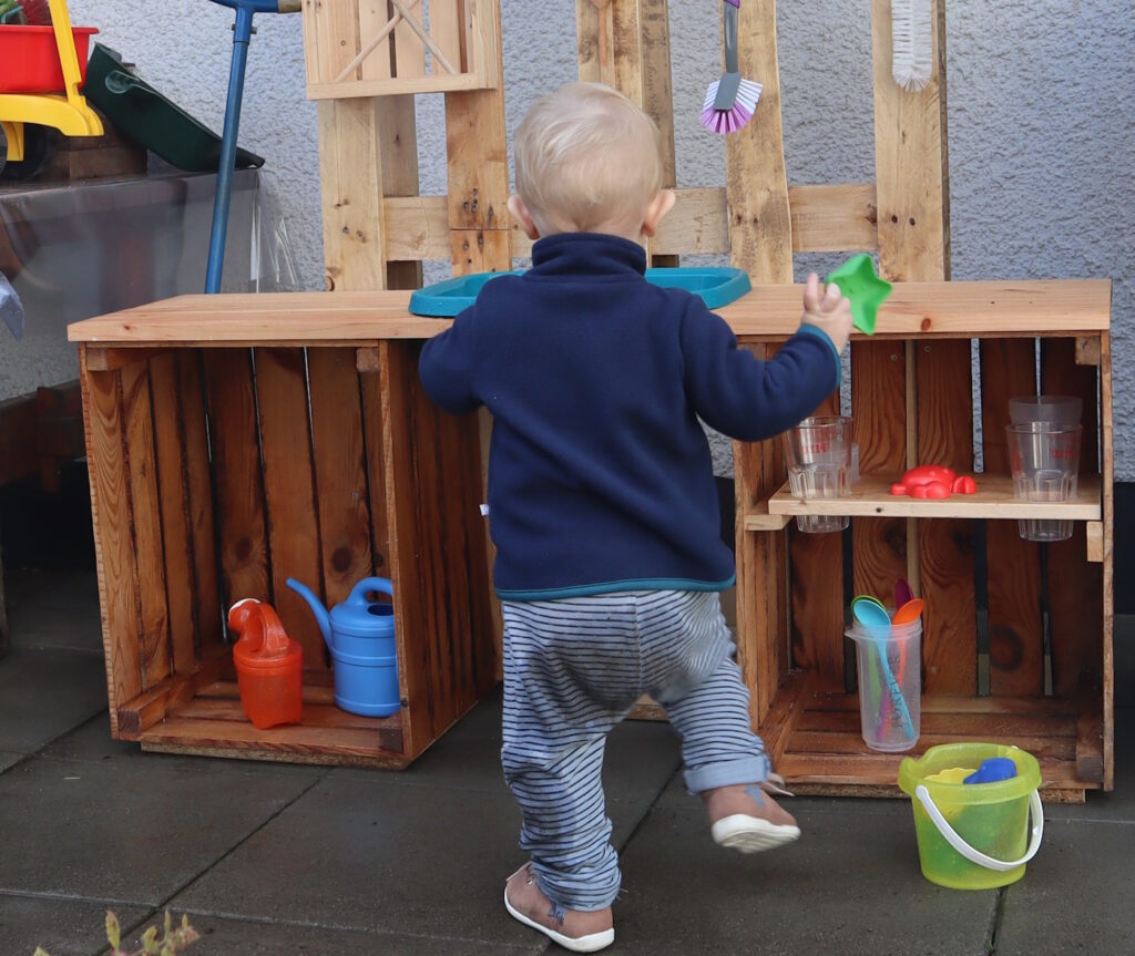 Das Foto zeigt ein Kind, das in der Matschküche spielt