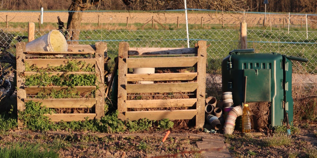Das Foto zeigt zwei Holzkomposter und einen Komposter aus Plastik