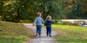Das Foto zeigt zwei Kinder die auf einem Weg durch den Garten rennen