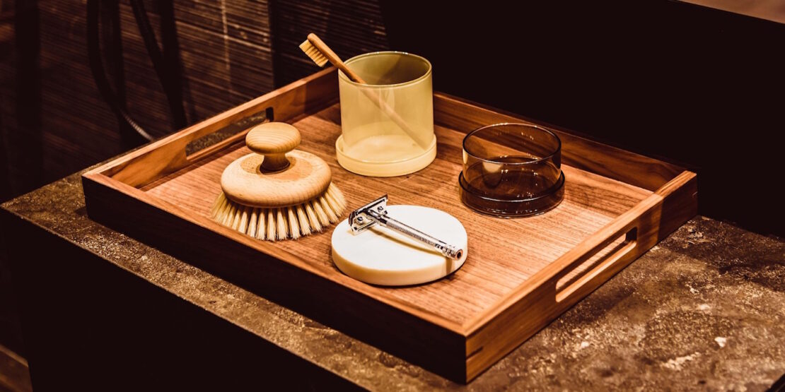 Das Foto zeigt ein Tablett aus Bambus mit einer Zahnbürste, einem Rasierer und einer Bürste