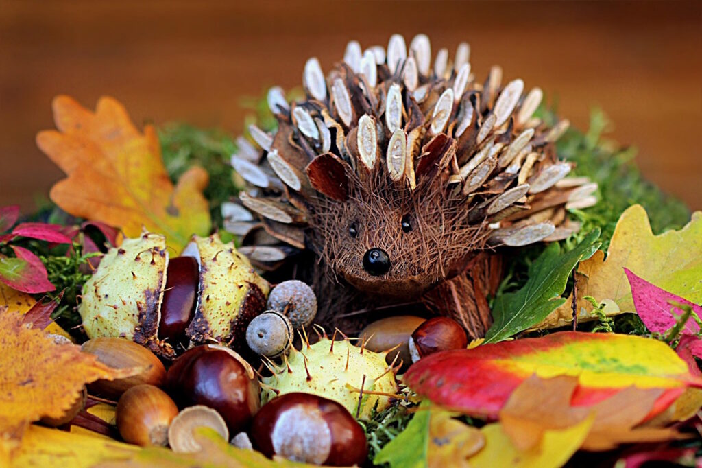 Das Foto zeigt einen kleinen Igel aus Holz und Kastanien mit Herbstblättern