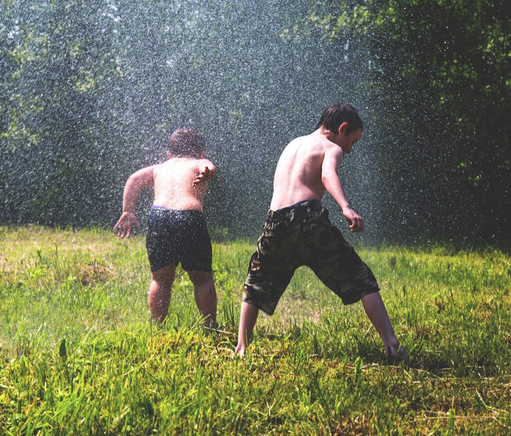 Das Foto zeigt zwei Kinder, die eine Wasserschlacht machen